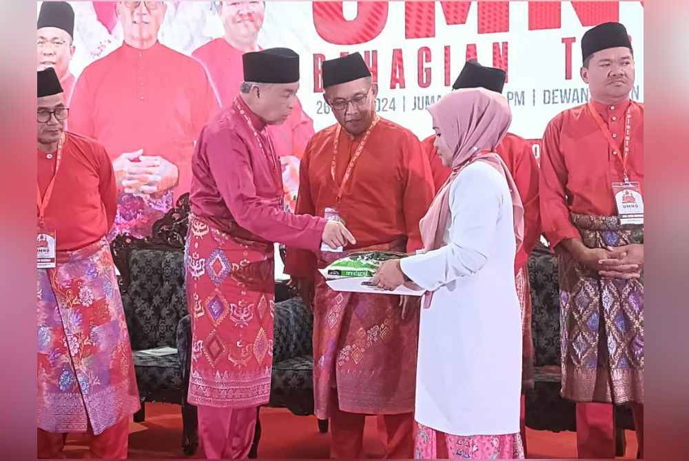 Ahmad Zahid (tengah) menyampaikan sumbangan kepada penerima selepas merasmikan Mesyuarat Perwakilan UMNO Bahagian Tebrau di Dewan Taman Adda Height, Tebrau, Johor Bahru pada malam Jumaat.