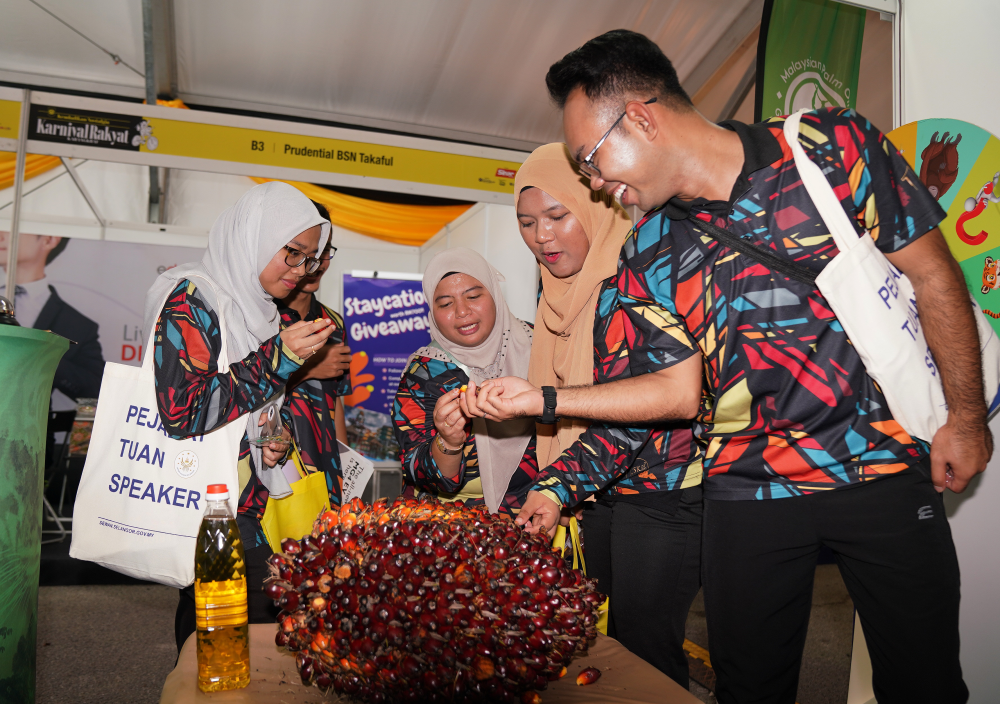 Orang ramai cuba meneka berat buah sawit di reruai MPOGCF.
