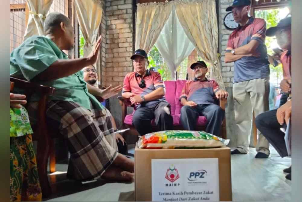 Mohd Na'im (tengah) meluangkan masa ke rumah asnaf penerima bantuan zakat MAIWP.