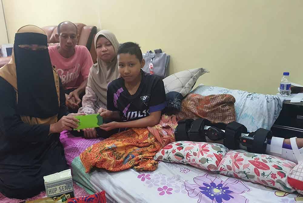 Maznah (kiri) menyerahkan sumbangan kepada Nur Fisya Atira di kediamannya di Taman Sepadu, Tasek Gelugor pada Sabtu.