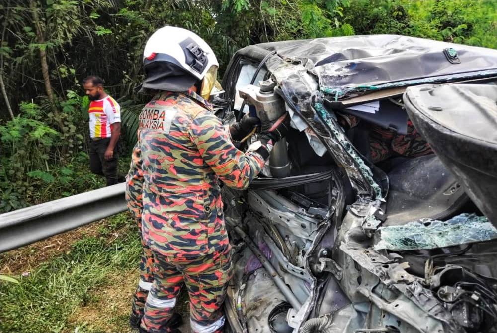 Anggota bomba mengeluarkan mangsa yang tersepit dalam Hilux terbabit. Foto ihsan JBPM