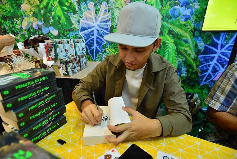 Arifful Baqi menandatangani karya 'Pemutus Nyawa' sempena pelancarannya pada Sabtu.