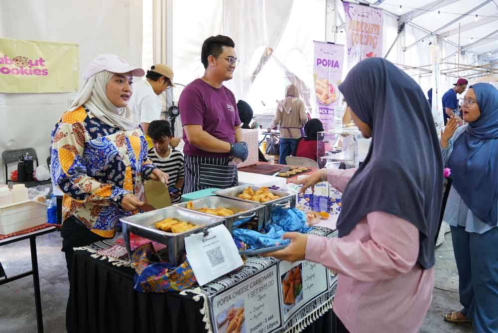 Seorang pengunjung membeli di gerai jualan Papakim Delights di Karnival Rakyat Karangkraf.