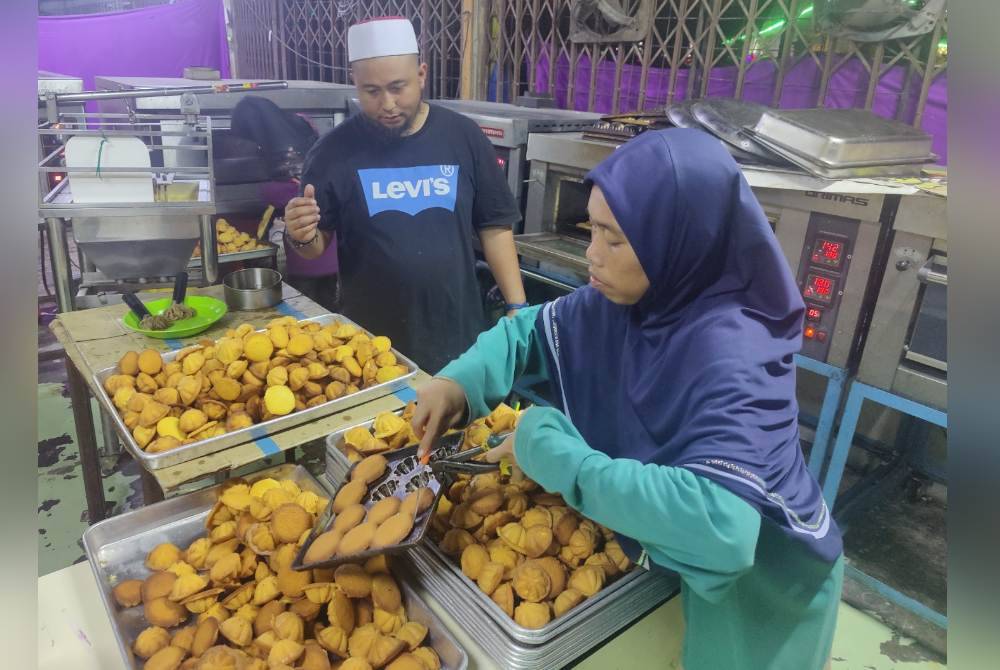 Siti Idayou dan suaminya menyusun kuih baulu sebelum dimasukkan ke dalam bekas.