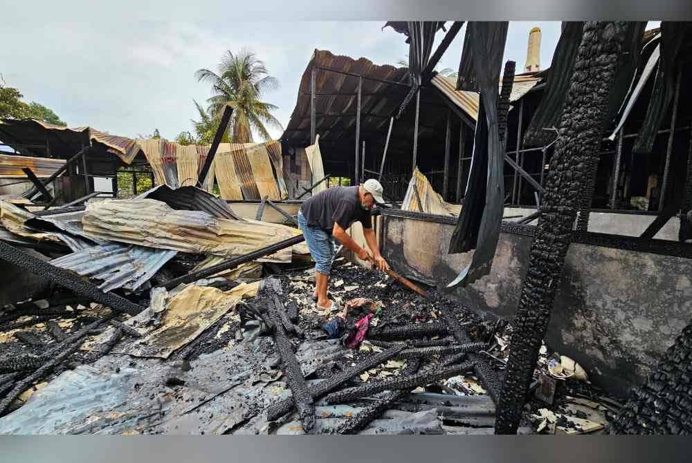 Mior Shapie cuba mencari barangan berharga dalam timbunan sisa kebakaran di rumahnya di Kampung Manjoi.