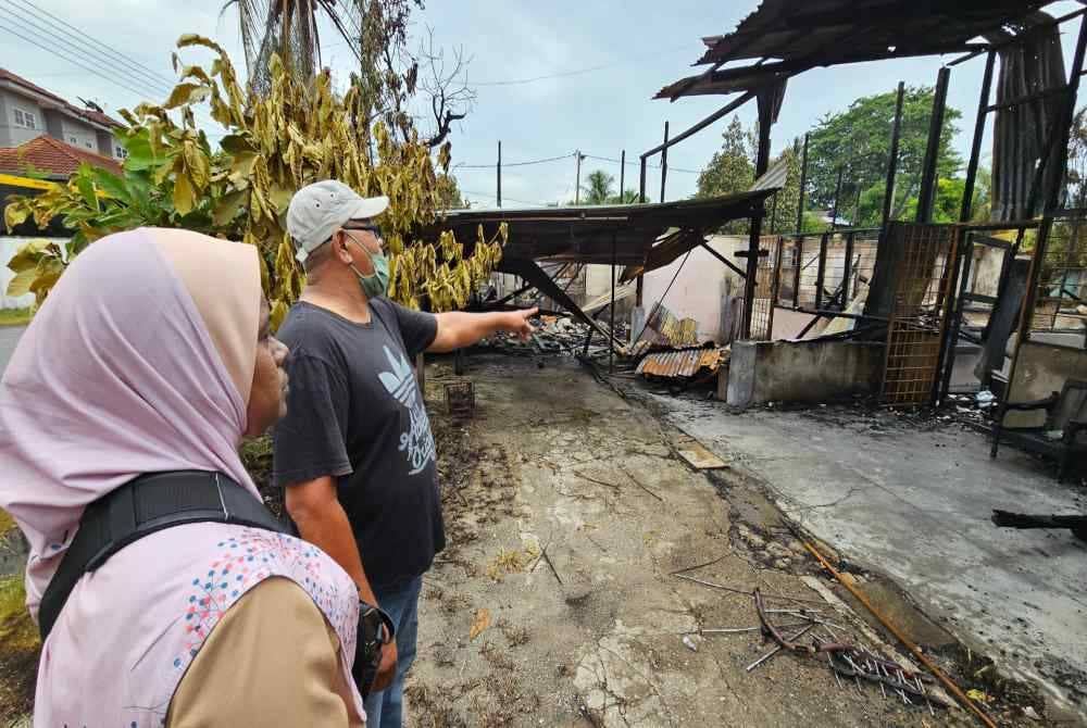 Mior Shapie bersama isterinya melihat keadaan rumah mereka yang musnah dalam kebakaran di Kampung Manjoi pada Ahad.