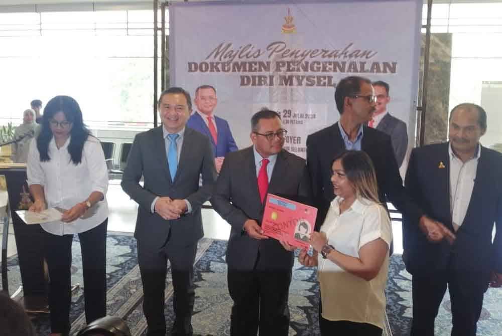 Amirudin (tiga dari kiri) menyampaikan dokumen pengenalan diri kepada salah seorang penerima.