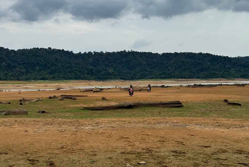 Penduduk kampung di sekitar kawasan Tasik Pedu menaiki motosikal untuk melihat sebahagian kawasan tasik berkenaan yang kering.