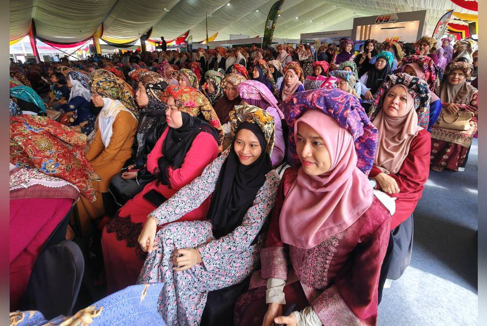 Wanita-wanita kelihatan manis berbaju kurung sambil memakai telepuk.