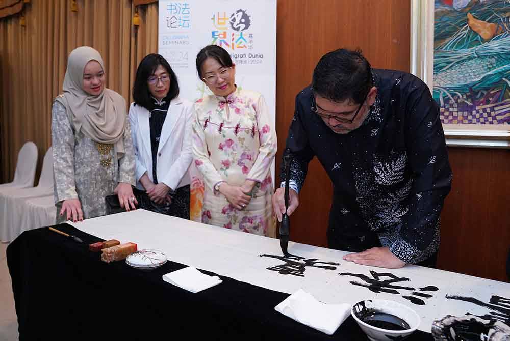 Swee Kheng (kanan) melakukan demontrasi menulis kaligrafi disaksikan oleh Christina (dua dari kanan) pada Majlis Pelancaran Karnival Kaligrafi Dunia Kuala Lumpur 2024 di Kompleks Kraf Kuala Lumpur pada Selasa. Foto Sinar Harian - MOHD HALIM ABDUL WAHID