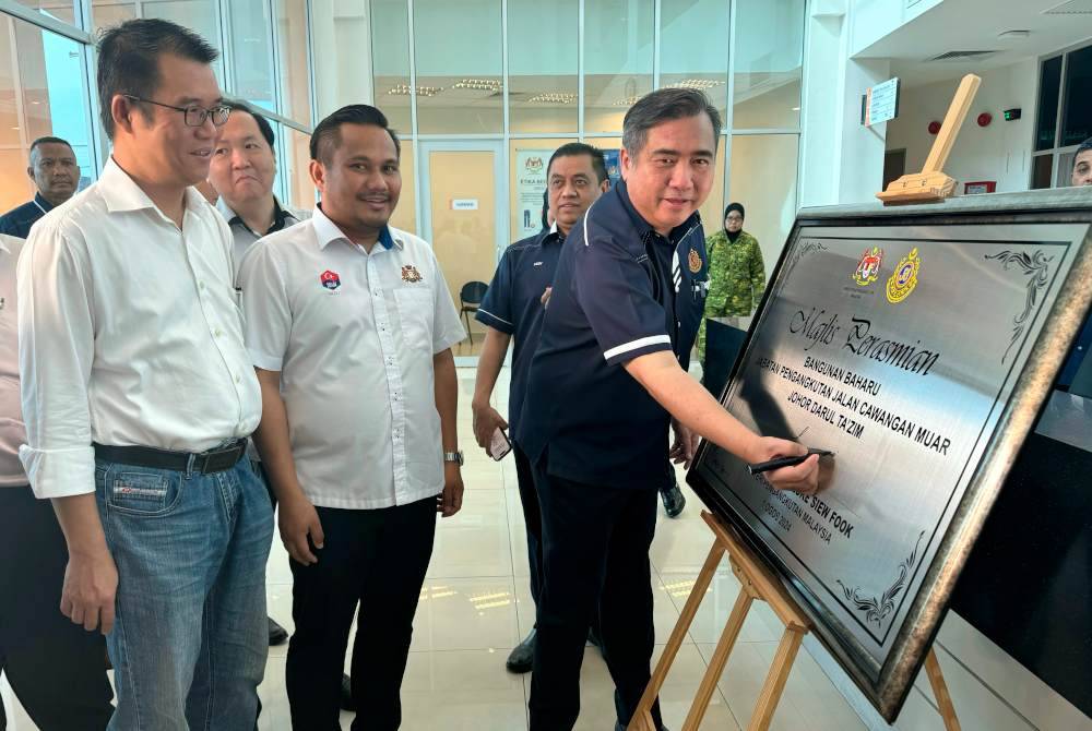 Anthony (kanan) menurunkan tandatangan pada plak perasmian Bangunan Baharu JPJ Cawangan Muar. Foto Bernama