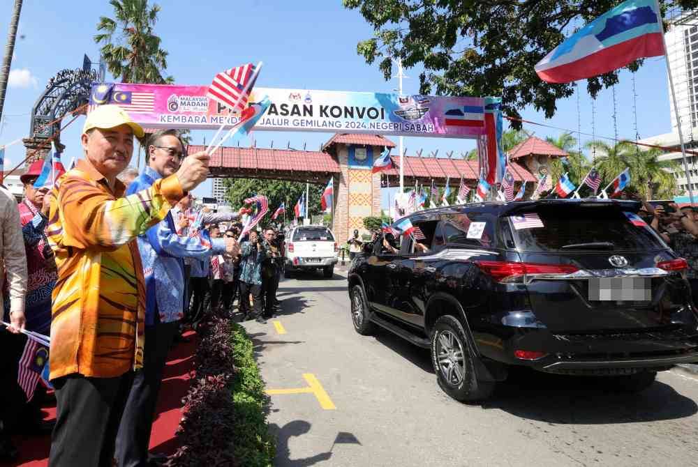 Hajiji bersama Menteri Kewangan, Datuk Seri Masidi Manjun mengibarkan Jalur Gemilang dan bendera Sabah ketika melepaskan Konvoi Merdeka. Foto Bernama