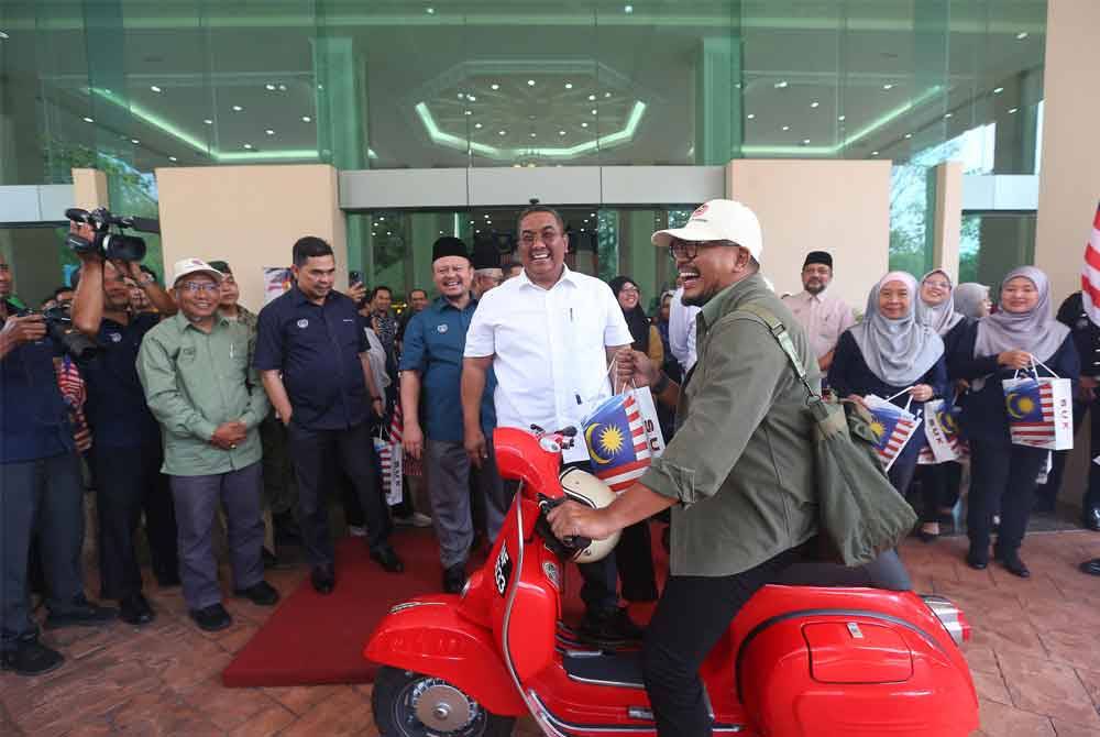 Sanusi menyerahkan Jalur Gemilang kepada wakil jabatan dan peserta konvoi Jiwa Merdeka di Wisma Darul Aman.
