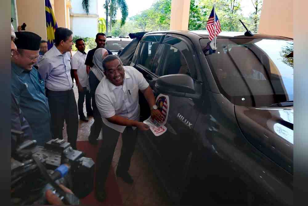 Sanusi menampal pelekat konvoi Jiwa Merdeka pada kenderaan jabatan kerajaan di Wisma Darul Aman.