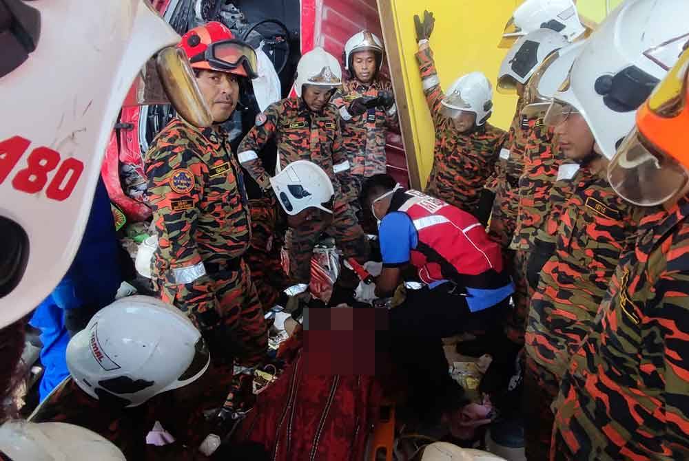 Anggota bomba membantu mengeluarkan mangsa yang ditemui dibawah treler yang terbabas merempuh rumah di Kampung Ketapang Hilir, Pekan pada Sabtu.