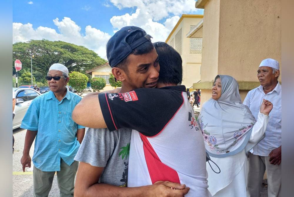 Mohd Fakrul Hafiz dipeluk oleh saudaranya kerana tidak dapat menahan sebaik ketika menuntut jenazah adiknya, Nurnazatul Fasiha di Hospital Pekan pada Sabtu.