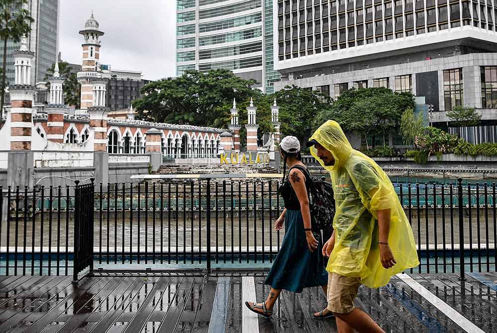 Para pelancong yang mengunjungi Dataran Merdeka dan kawasan River of Life dengan berlatar belakangkan Masjid Jamek Kuala Lumpur menggunakan baju hujan ketika tinjauan foto Bernama di sekitar ibu kota hari ini.