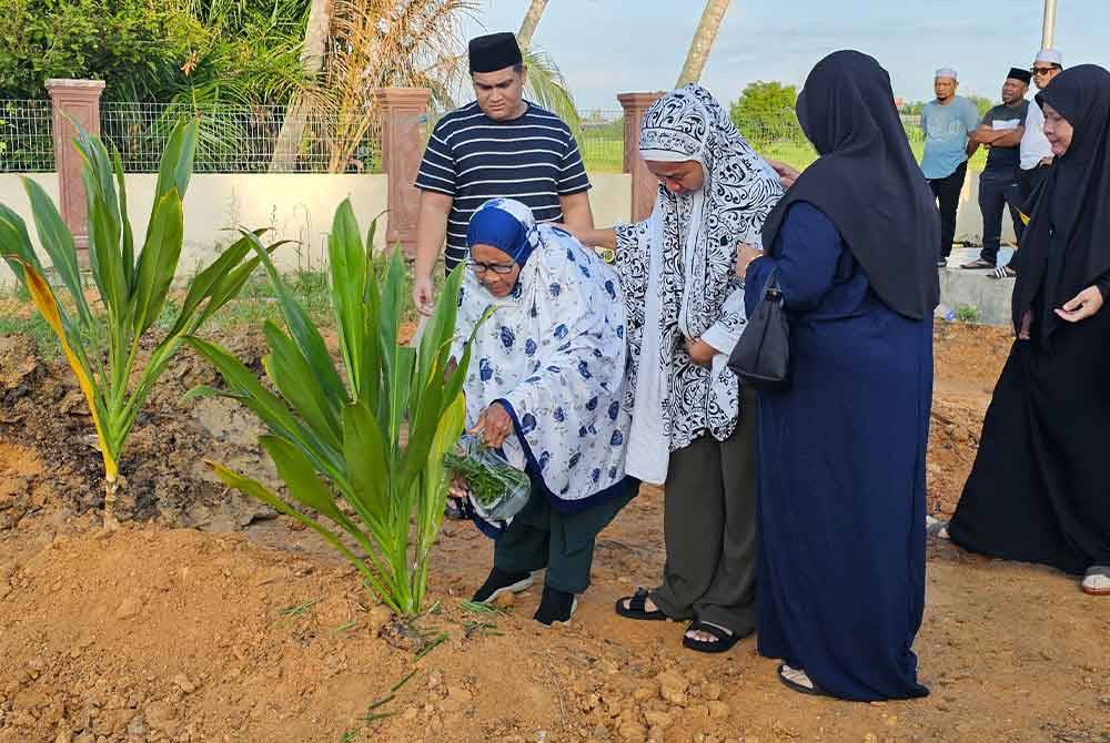 Rokiah (tiga dari kanan) tidak dapat menahan sebak ketika menyiram pusara anaknya, Allahyarham Muhammad Firdaus.