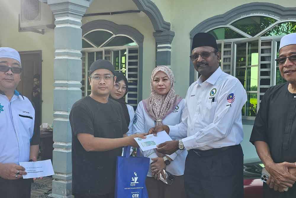 Ikmal Azam Thanaraj (dua dari kanan) menyerahkan sumbangan kepada ahli keluarga Allahyarham Muhamad Firdaus, Muhammad Amirul Shafiq ketika hadir di kediaman mangsa di Parit Jay, Matang Jelutong pada Isnin.