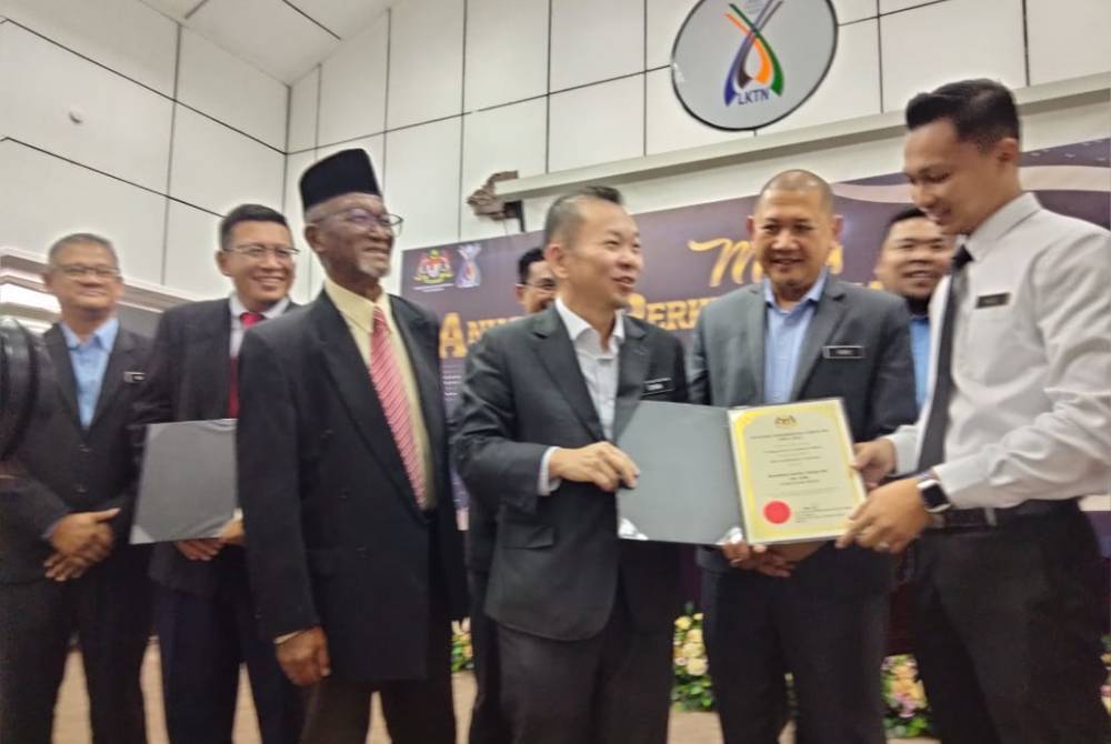 Foong Hin (tengah) melihat sijil APC kakitangan LKTN selepas merasmikan Majlis Perhimpunan Bulanan dan Anugerah Perkhidmatan Cemerlang (APC) 2023 pada Selasa.