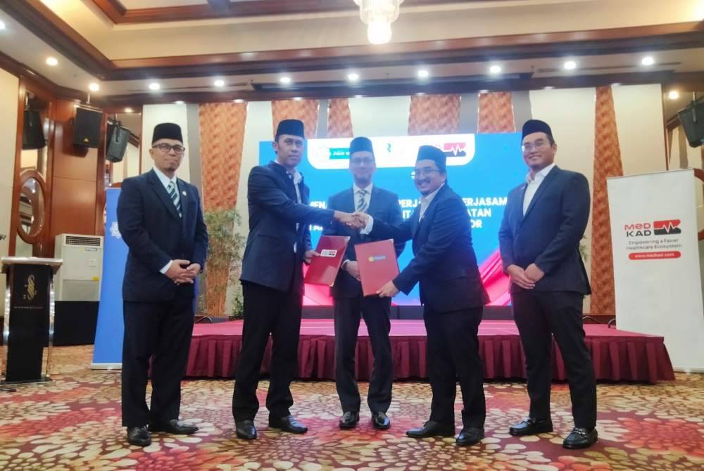 Mohd Sabirin (dua dari kiri) dan Ezuan (dua dari kanan) bertukar dokumen kerjasama disaksikan Dr Tunku Muzafar Shah (tengah).