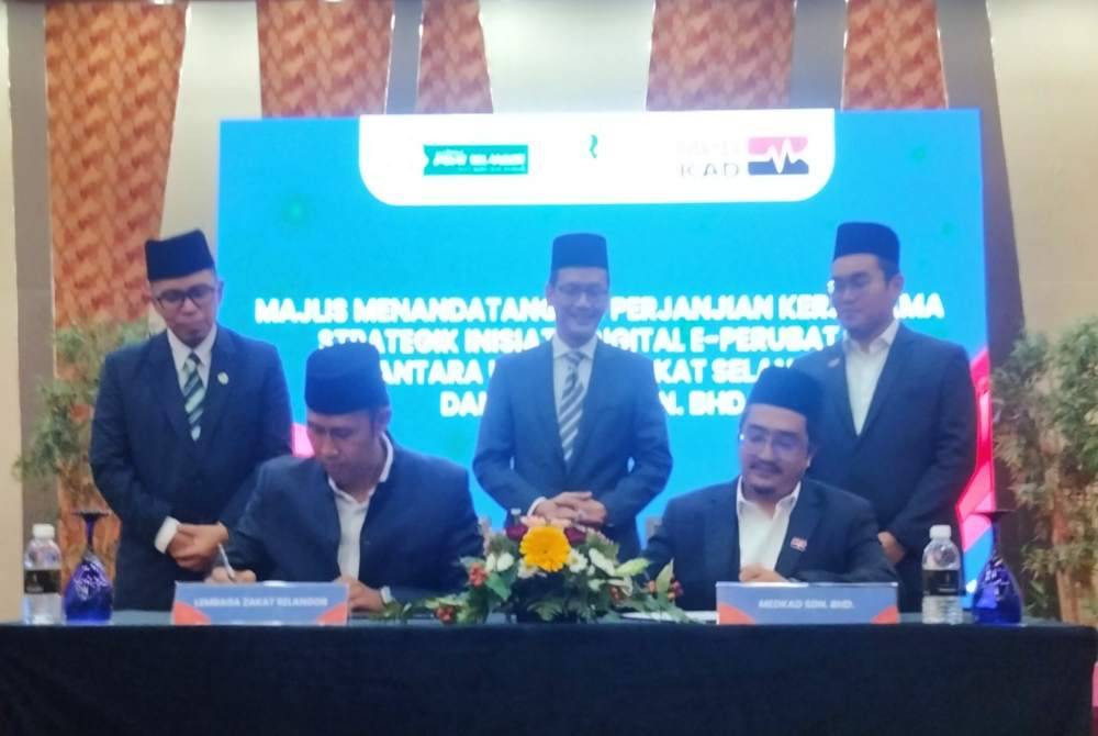 Perjanjian kerjasama ditandatangani Mohd Sabirin (duduk kiri) Ezuan (duduk kanan) disaksikan Dr Tunku Muzafar Shah (tengah).