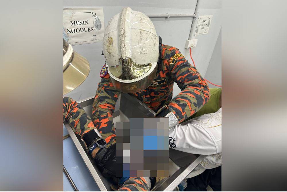 Anggota bomba mengeluarkan tangan kanan mangsa yang tersepit itu dengan menggunakan peralatan khas. Foto JBPM