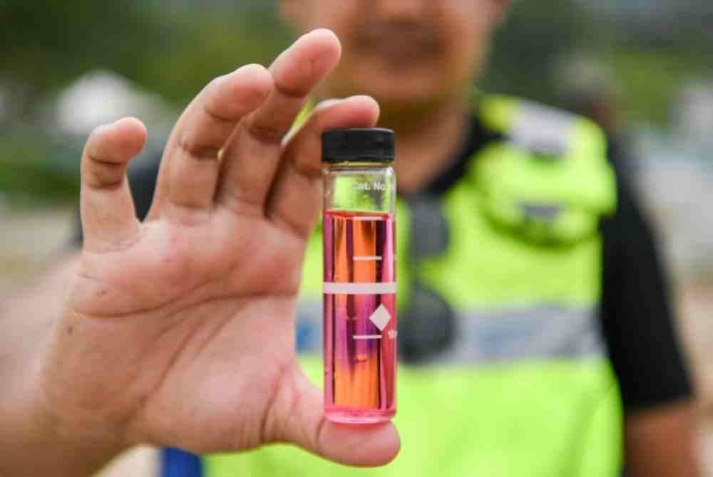 Penguatkuasa SPAN menunjukkan sampel air yang telah terbukti dirawat disambung secara tidak sah di sebuah tapak pembinaan projek landasan kereta api di Taman Melati, Gombak. Foto Bernama