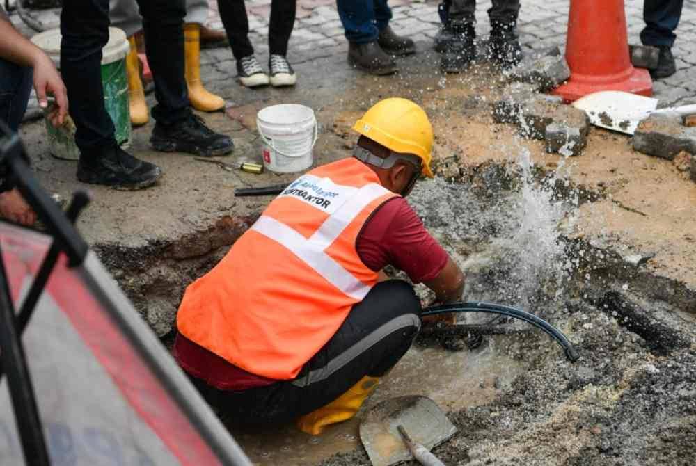 Anggota penguatkuasa SPAN melakukan kerja-kerja pemotongan pada saluran air yang disambung secara tidak sah di sebuah tapak pembinaan projek landasan kereta api di Taman Melati, Gombak. Foto Bernama
