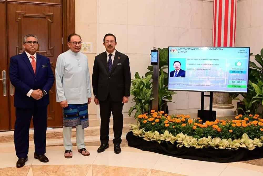 Mohd Zuki (kanan) merakamkan potret bersama Anwar (tengah) dan Ketua Pengarah Unit Komunikasi Awam Swasta (UKAS), Datuk Seri Shamsul Azri Abu Bakar di hari terakhirnya sebelum bersara pada Sabtu.