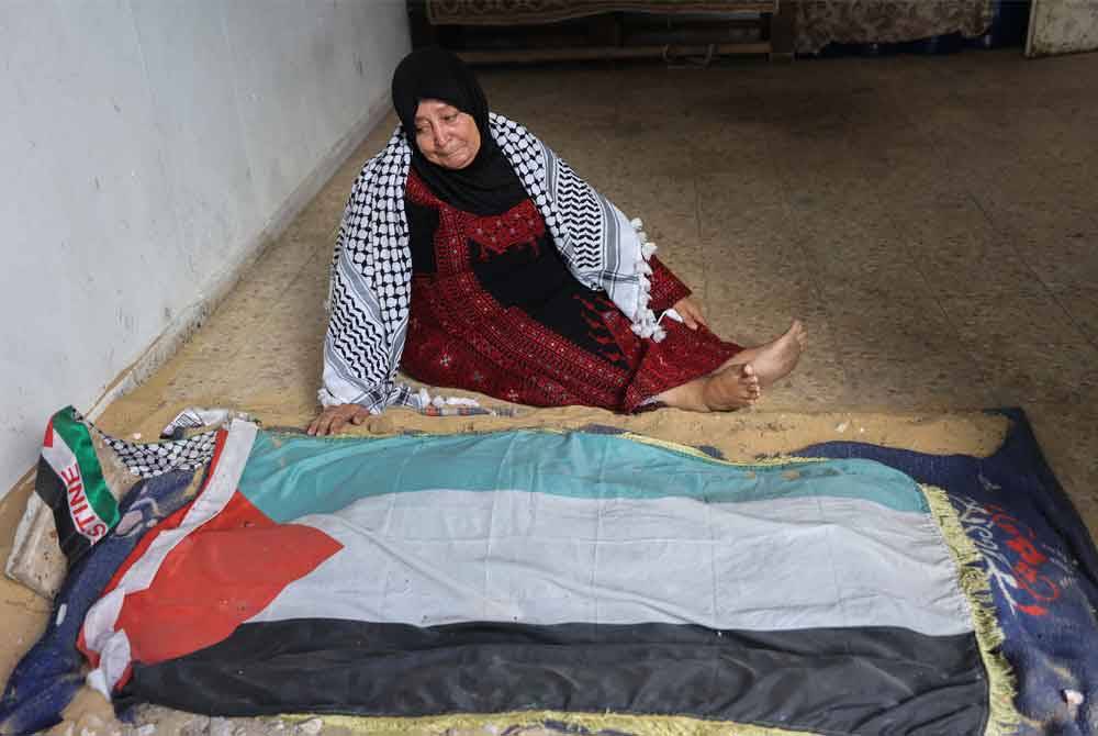 Maryam Abu Obeid, 65, duduk di sisi pusara cucunya, Khaled
di sebuah tempat perkuburan sementara di kawasan kejiranan
Sheikh Radwan di tengah Gaza.