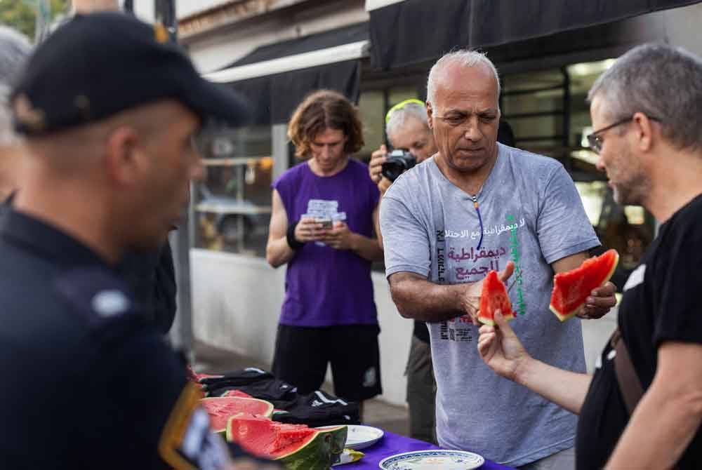 Aktivis sayap kiri Israel, mengagihkan potongan tembikai yang menjadi simbol Perang Gaza sebagai membantah larangan polis yang menghalang peserta protes mengibarkan bendera Palestin ketika demonstrasi di bandar Haifa.