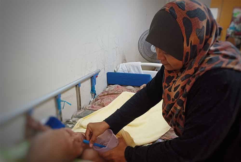Fatimah diberikan susu oleh anaknya, Normawati dalam keadaan terbaring di Perumahan Kampung Padang pada Sabtu.