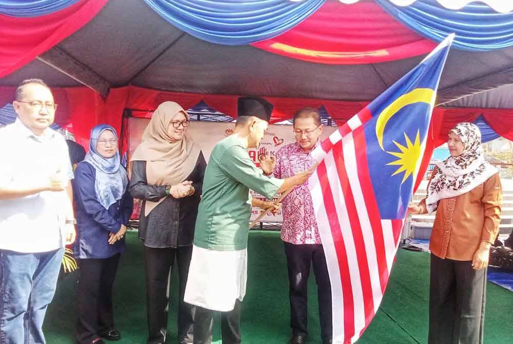 Amran (empat kiri) ketika menyerahkan Jalur Gemilang kepada Adnan (dua kanan)