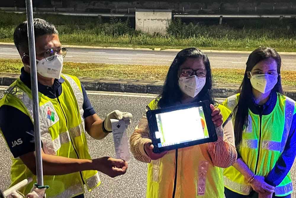 Sharifah Zakiah (tengah) menunjukkan keputusan pengukuran asap menggunakan meter penguji asap.