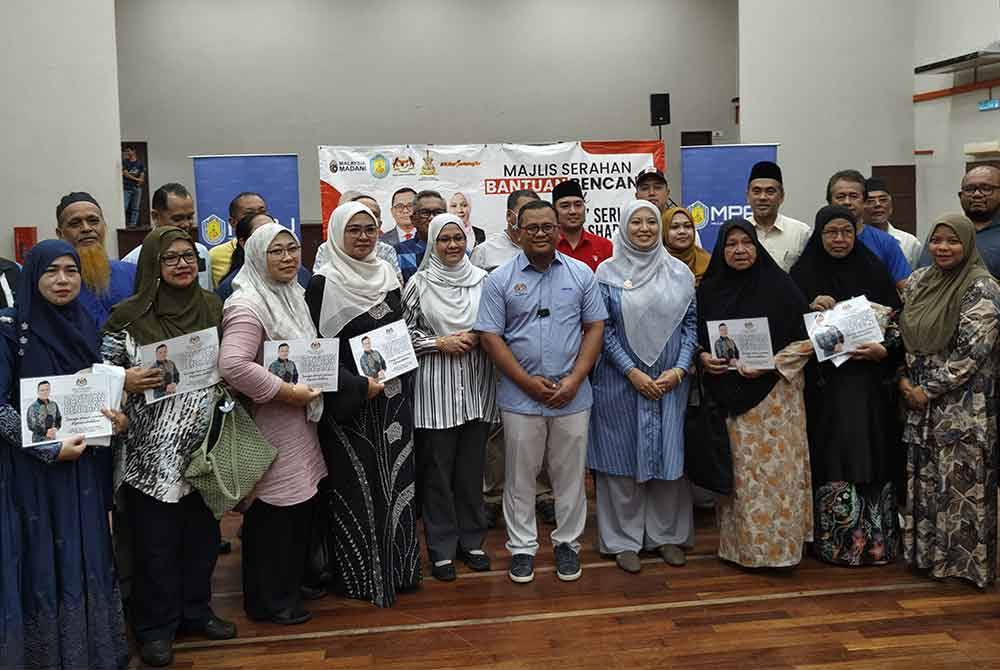 Amirudin bergambar bersama penerima sumbangan terdiri daripada peniaga Medan Selera AU5 yang terjejas kebakaran dalam kejadian Julai lalu.