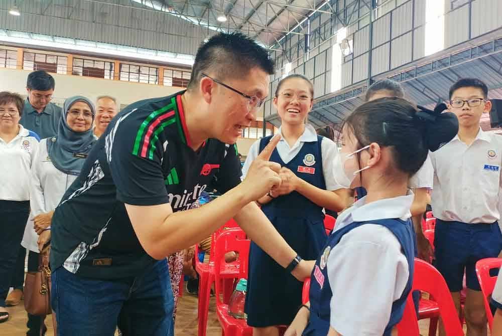 Kah Woh menyantuni murid semasa hadir ke Program Semarak Bahasa Kebangsaan Kampung Baru Pokok Assam di Sekolah Jenis Kebangsaan Cina (SJKC) Pokok Assam di Taiping pada Ahad.