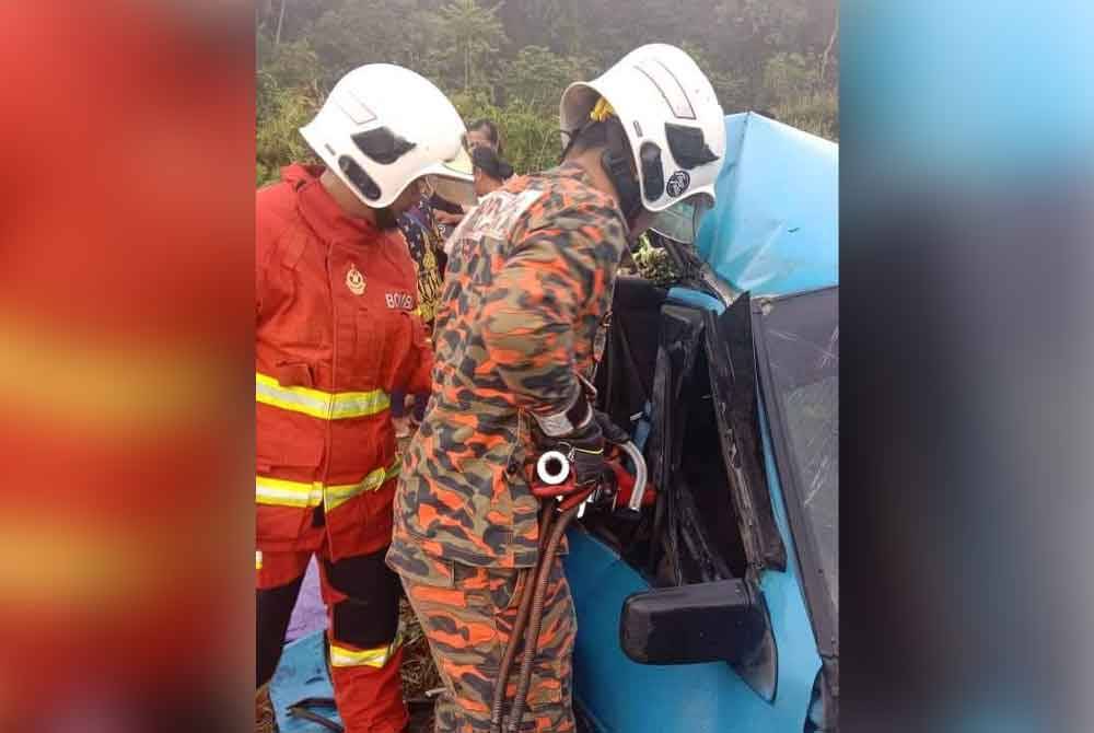 Anggota bomba berusaha mengeluarkan mangsa dari kereta yang remuk.