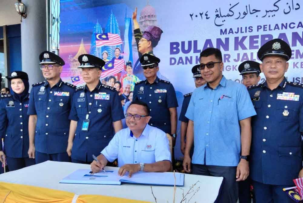 Naim Fahmi (duduk, tengah) menandatangani buku kehadiran tetamu pada Majlis Pelancaran Bulan Kebangsaan Dan Kibar Jalur Gemilang 2024 Peringkat Negeri Kelantan pada Isnin.