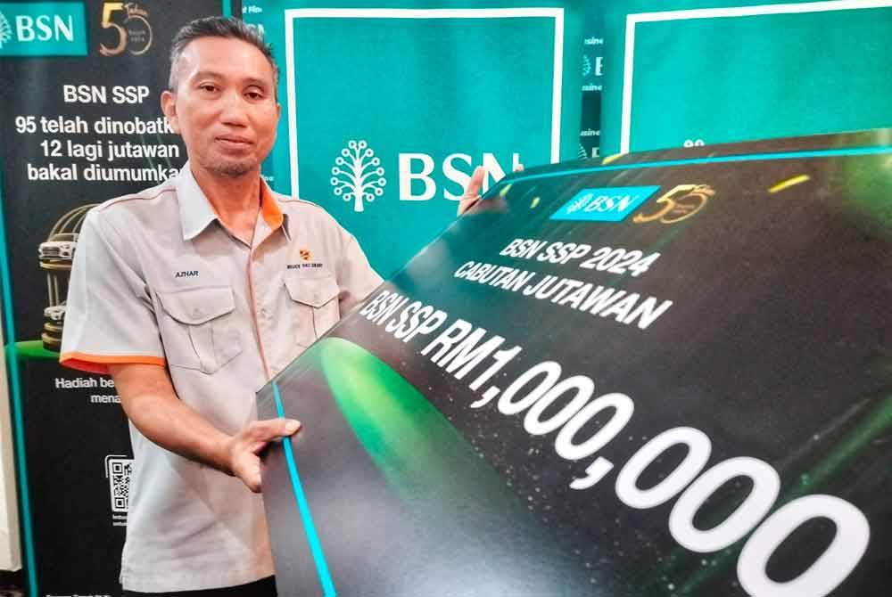 Mohd Azhar menunjukkan replika cek selepas beliau diumumkan sebagai pemenang Cabutan Jutawan BSN SSP yang ke-102.