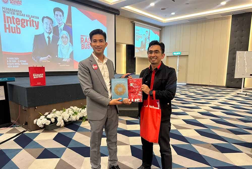 Nor Hannan (kanan) menerima cenderamata daripada Penceramah Rasuah Busters, Mohd Zikrul Hakim Noor (kiri).