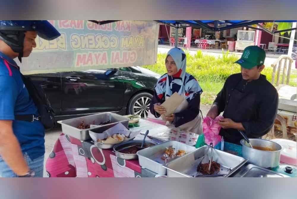 Faizah (tengah) menjual makanan dengan dibantu anaknya di tepi jalan di Mergong, Alor Setar.