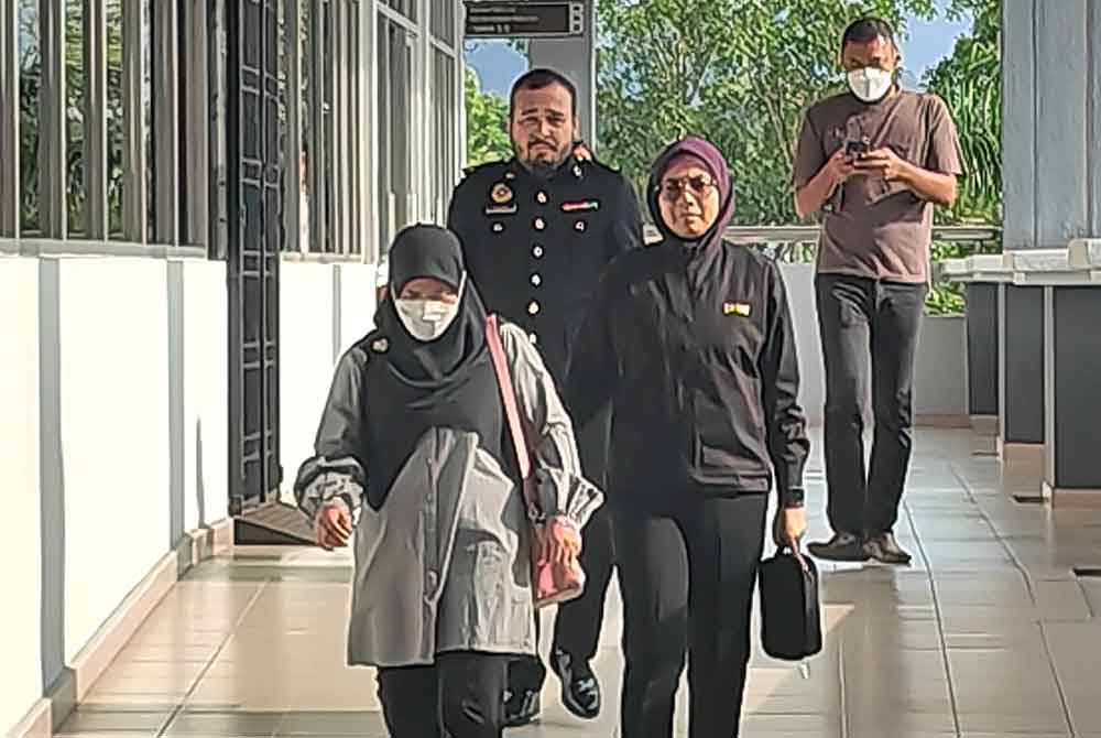 Foziana (kiri) diiring pegawai SPRM ketika hadir ke mahkamah.