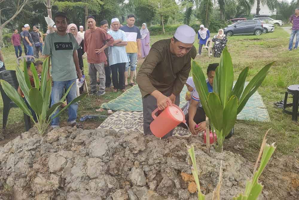 Mohd Azril menyiram air ke kubur anaknya di Tanah Perkuburan Islam Kampung Teluk Piai di sini pada Rabu.