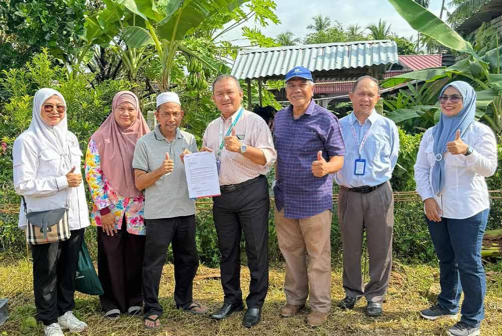 Wan Ishak (tengah) menyampaikan watikah berhubung pembinaan rumah Ahmad Rodzi (tiga dari kiri).