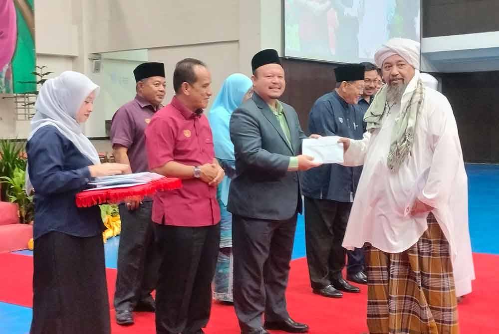 Mohd Azam (dua kanan) menyampaikan bantuan kepada wakil institusi agama sempena Majlis Pemberian Bantuan Operasi dan Agihan Wakalah Zakat pada Rabu.