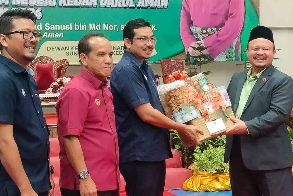 Mohd Azam (kanan) menerima cenderahati ketika hadir mewakili Muhammad Sanusi semasa Majlis Pemberian Bantuan Operasi dan Agihan Wakalah Zakat kepada Institusi Pendidikan Islam Negeri Kedah Tahun 2024.