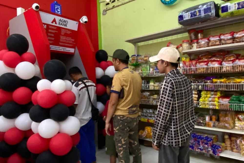Penduduk beratur untuk menggunakan perkhidmatan mesin ATM yang disediakan.