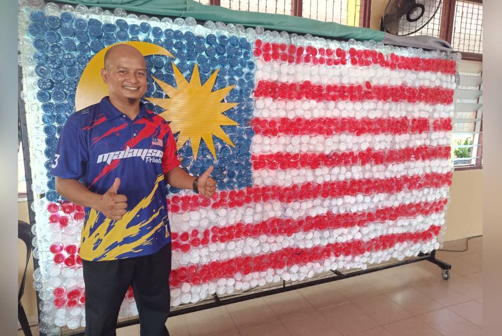 Mohamad Azrani bergambar di hadapan bendera yang dihasilkannya