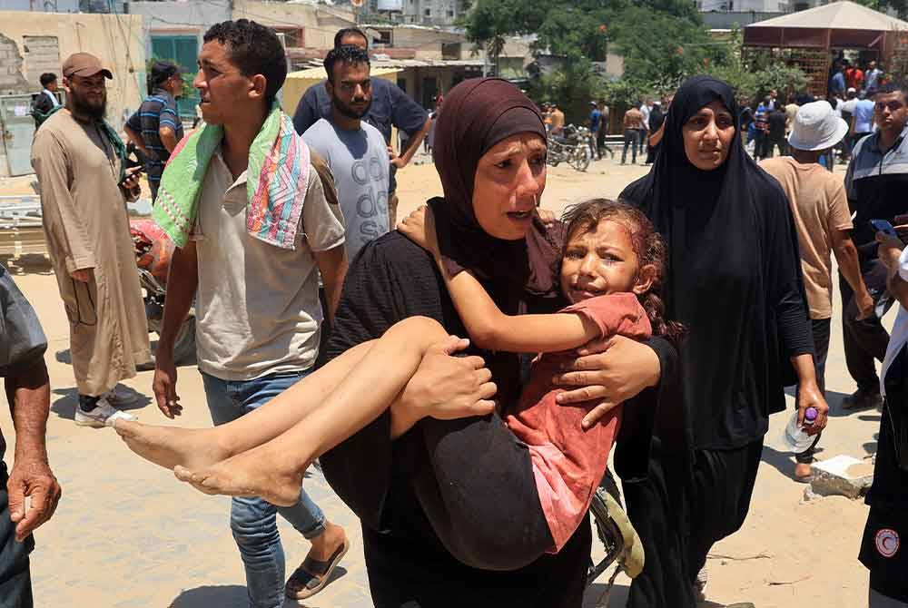 Seorang wanita membawa anaknya yang cedera ke Hospital Nasser di Khan Yunis selepas serangan udara Israel membunuh 90 orang di kem Al-Mawasi. Foto AFP